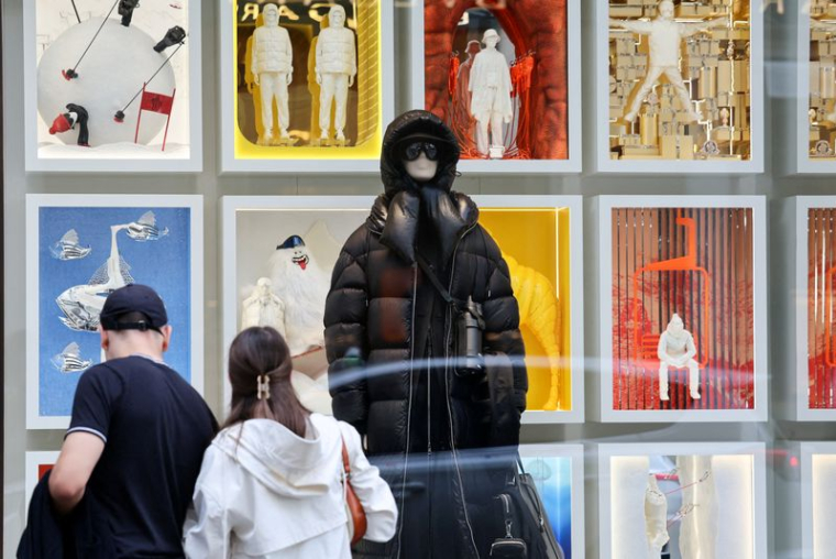 Des passants regardent la vitrine d'un magasin Moncler à Milan