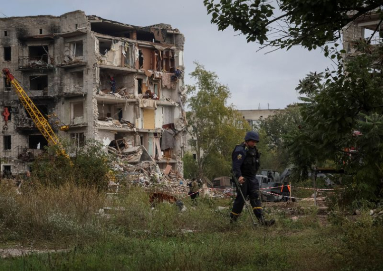 Les autorités travaillent autour et à l'intérieur d'un immeuble résidentiel endommagé par une frappe militaire russe à Izium, Ukraine