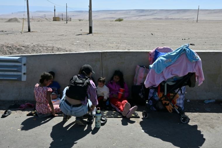 Des migrants attendent près du poste frontière de Cachalluta avec le Pérou, à environ 25 km au nord d'Arica, au Chili, le 30 novembre 2025 ( AFP / RODRIGO ARANGUA )