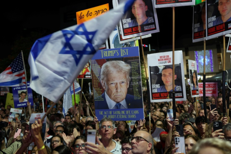 Des manifestants brandissent des drapeaux israéliens et américains, ainsi que des photos d'otages retenus à Gaza,  lors d’un rassemblement à Tel-Aviv, le 11 octobre 2025 ( AFP / Jack GUEZ )