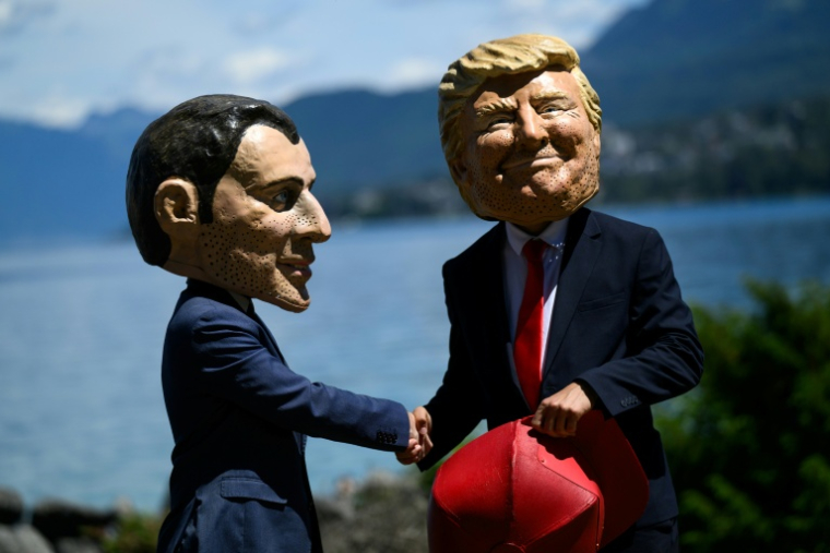 Des manifestants affublés de grosses têtes caricaturant le président français Emmanuel Macron et le président américain Donald Trump, posent lors d'un événement organisé par l'ONG Oxfam, à Publier, près d'Evian, dans l'est de la France, le 14 juin 2026 ( AFP / JEFF PACHOUD )