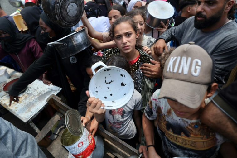 Des enfants se pressent à une distribution de repas chauds à Nousseirat, dans le centre de la bande de Gaza, le 4 juin 2025 ( AFP / Eyad BABA )