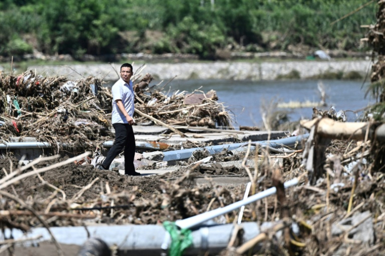 Un homme marche au milieu des dégâts causés par les pluies diluviennes qui ont frappé Pékin, dans le discrit de Huairou, le 30 juillet 2025 ( AFP / Pedro Pardo )