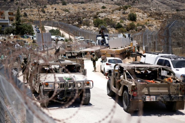Des véhicules militaires israéliens longent la barrière frontalière, près de la ville de Majdal Shams, sur les hauteurs du Golan annexées par Israël, le 17 juillet 2025 ( AFP / Jalaa MAREY )