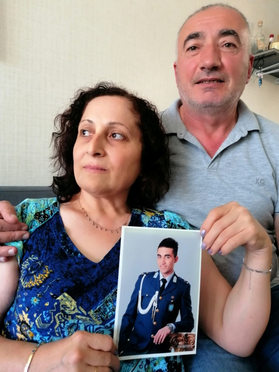 Kerban Kalin (g) et Ali Kalin (d) montrent une photo de leur fils, l'élève-officier Alper Kalin, qui purge une peine de prison à vie après la tentative de coup d'État de juillet 2016 en Turquie, chez eux à Ankara, le 12 juillet 2026 ( AFP / Anne CHAON )