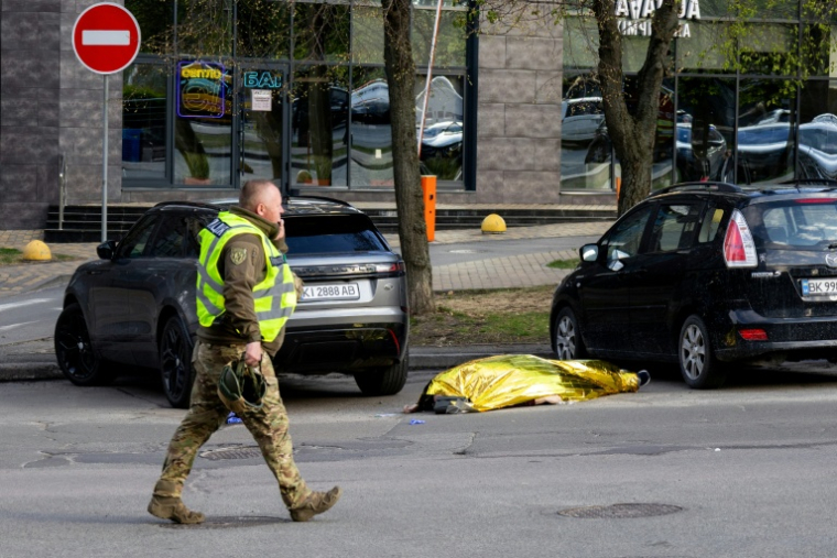 Un policier passe devant le corps d'une victime d'une fusillade près d'un supermarché de Kiev, la capitale ukrainienne, le 18 avril 2026 ( AFP / Serhii Okunev )