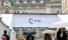 Des gens s'abritent de la pluie en passant devant un accès à la Conférence de Munich sur la sécurité (MSC), le 12 février 2026 à Munich ( AFP / THOMAS KIENZLE )