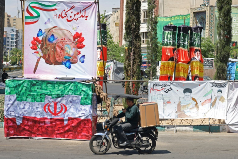 Un automobiliste passe devant une banderole représentant le guide suprême iranien tué, l'ayatollah Ali Khamenei, ainsi qu'un drapeau iranien, à Téhéran le 29 avril 2026 ( AFP / ATTA KENARE )