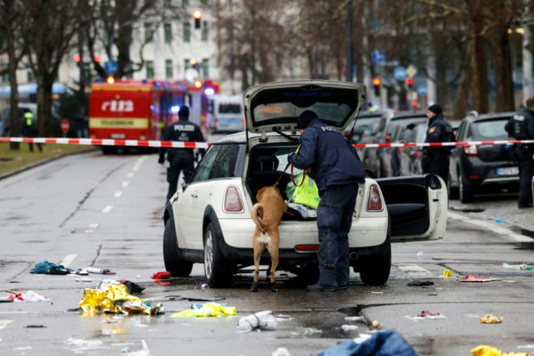 Un policier et son chien fouillent une voiture sur les lieux où un homme a foncé dans une foule dans la ville de Munich, le 13 février 2025, faisant deux morts et une quarantaine de blessés ( AFP / Michaela STACHE )