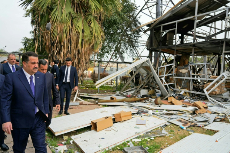 Photo prise et transmise par les services de presse du Premier ministre irakien, le 22 mars 2026, montrant le chef du gouvernement Mohammed Shia al-Sudani (G) inspectant les dégâts après une attaque de drone contre un bâtiment des services de renseignement à Bagdad ( IRAQI PRIME MINISTER'S PRESS OFFICE / - )