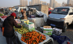 Un vendeur de fruits s'occupe d'un client sur un marché en plein air à Pékin, Chine