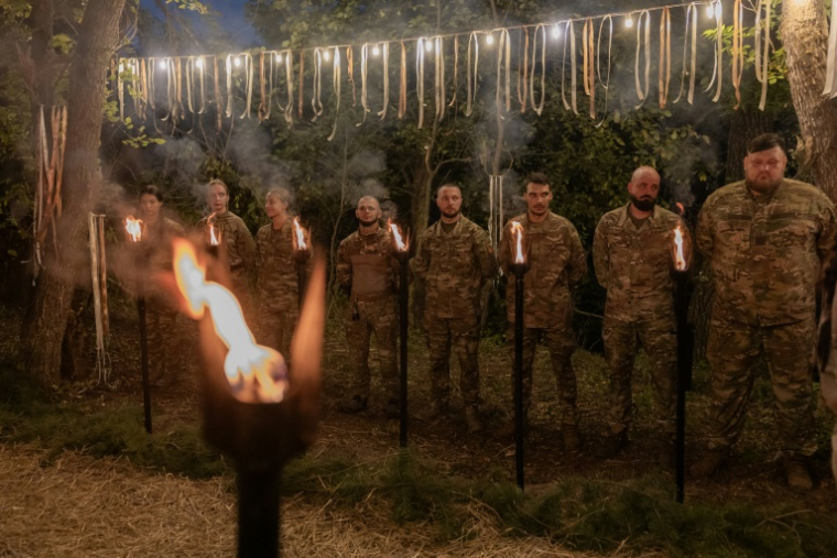 Des soldats ukrainiens  forment une haie d'honneur lors d'une "Mystérya", près d'Izium, dans la région de Kharkiv, en Ukraine, le 26 août 2026 ( AFP / Roman PILIPEY )