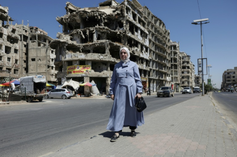 La députée syrienne Nour Jandali, une écrivaine, pose devant un bâtiment détruit à Homs, dans le centre de la Syrie, le 27 juillet 2026 ( AFP / Bakr ALkasem )