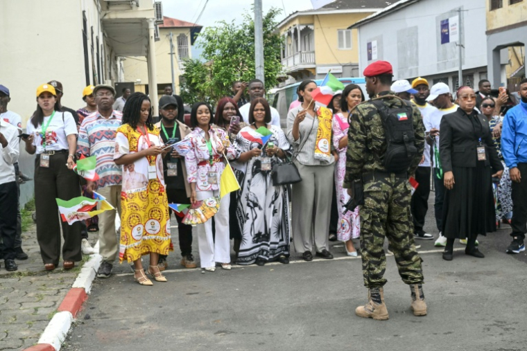 Un soldat de Guinée équatoriale monte la garde tandis que des habitants se rassemblent au bord de la route que le cortège du pape Léon XIV empruntera après son arrivée à Malabo, le 21 avril 2026 ( AFP / Alberto PIZZOLI )