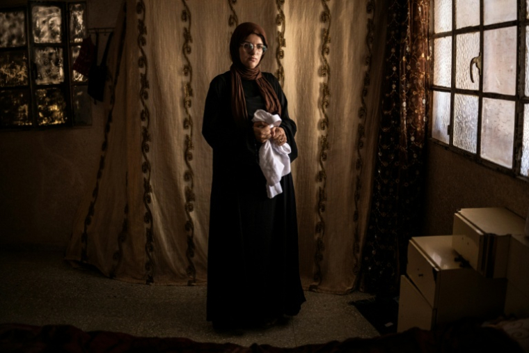Alia al-Hallaq, la mère de Mohammed, tué à 9 ans par un soldat israélien en octobre 2025, tient le thobe de son fils, dans le village d'al-Rihiya, en Cisjordanie occupée, le 16 juillet 2026 ( AFP / JOHN WESSELS )