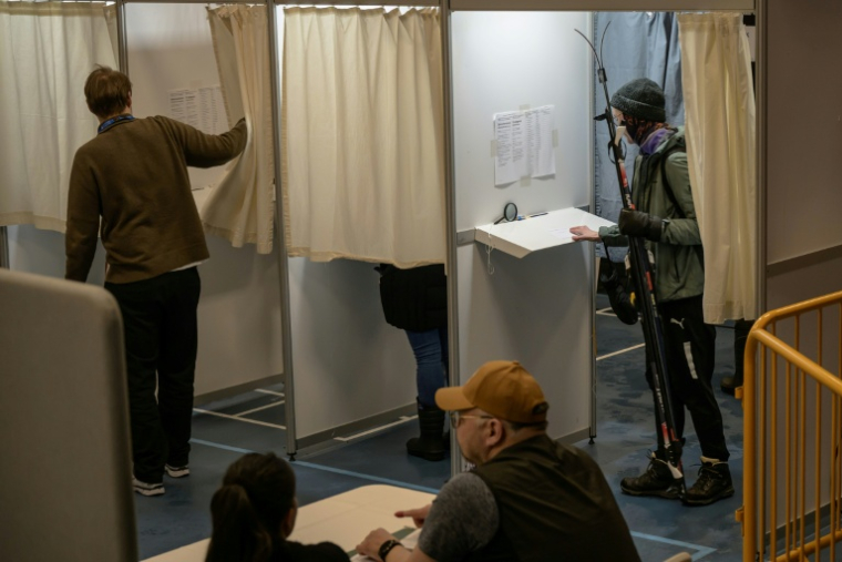 Une électrice entre dans l'isoloir avec ses skis pour voter aux élections législatives danoises à Nuuk, au Groenland, le 24 mars 2026 ( AFP / Florent VERGNES )