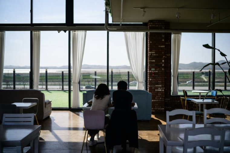 Des clients contemplent les montagnes de la Corée du Nord depuis le café Daonsoop, situé à moins de deux kilomètres de la frontière nord-coréenne à Paju, au nord de Séoul, le 24 avril 2025 en Corée du Sud ( AFP / ANTHONY WALLACE )