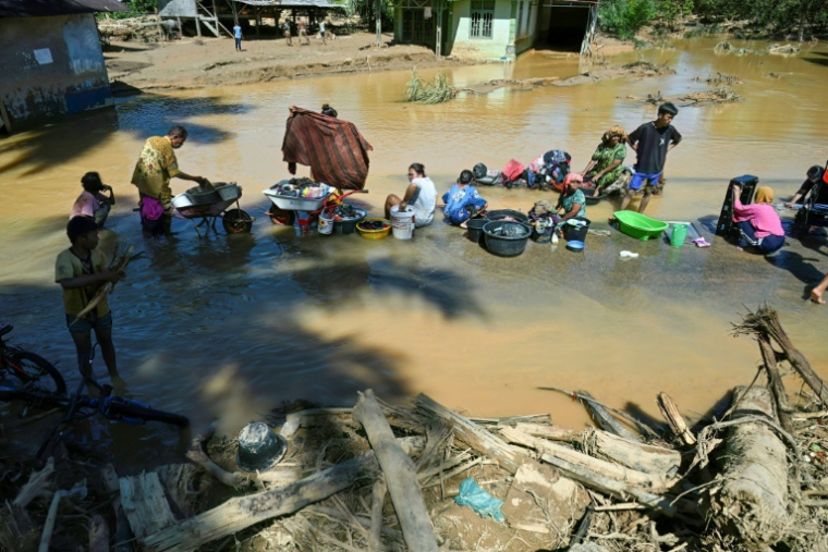 Des villageois lavent leurs vêtements dans une flaque d'eau après une crue soudaine qui a frappé leur village à Tukka, dans le district de Tapanuli central, province de Sumatra du Nord, le 3 décembre 2025 ( AFP / YT Hariono )