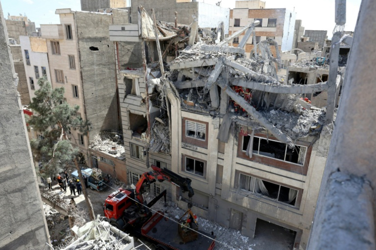 Des pompiers recherchent des victimes dans les décombres d'un immeuble résidentiel touché par une frappe aérienne, le 27 mars 2026 dans le sud de Téhéran, en Iran ( AFP / - )