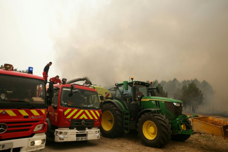 Des sapeurs-pompiers de la Brigade de sapeurs-pompiers de Paris ravitaillent leurs véhicules en eau à partir de la cuve du tracteur d'un agriculteur lors d'une intervention à Marcheprime, à l'ouest de Bordeaux, le 26 juillet 2026 ( AFP / ALAIN JOCARD )