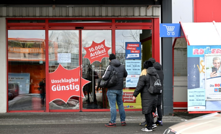 Des personnes se tiennent devant un magasin de meubles fermé en raison d’une panne de courant massive dans le quartier de Lichterfelde à Berlin, le 5 janvier 2026 ( AFP / RALF HIRSCHBERGER )