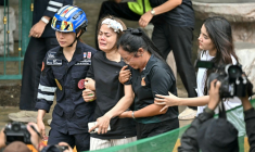 L'épouse (C) d'un professeur tué par un adolescent dans un lycée au nord de Bangkok est emmenée vers une ambulance, dans le district de Bang Kruai, en Thaïlande, le 7 août 2026 ( AFP / Lillian SUWANRUMPHA )