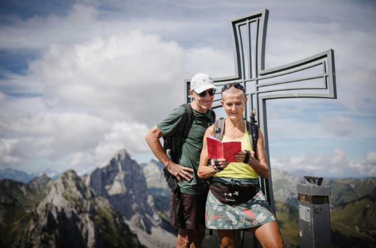 Patrick et Cathy, lisent le "Tinder des montagnes" au sommet de la Wandflue dans le canton de Fribourg, en Suisse, le 3 août 2025 ( AFP / GABRIEL MONNET )