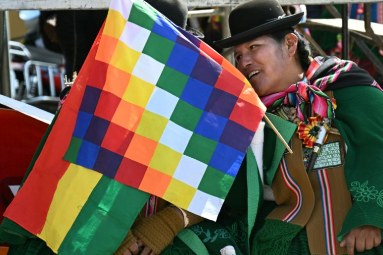 Une femme indigène brandit un drapeau Wiphala et un drapeau bolivien lors d’une réunion des dirigeants des "Ponchos Rouges" à Tilata, dans le département de La Paz, en Bolivie, le 18 juin 2026 ( AFP / AIZAR RALDES )