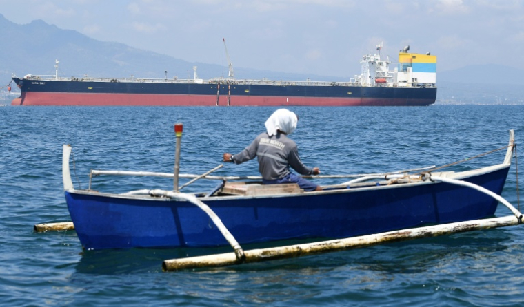 Un pêcheur passe à proximité du navire Sara Sky, battant pavillon sierra-léonais et transportant du pétrole brut russe, à l'ancrage au port de Limay, dans la province de Bataan, le 26 mars 2026 aux Philippines ( AFP / Ted ALJIBE )