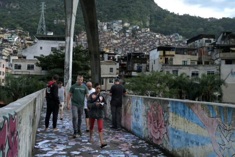 Des personnes traversent un pont jonché de tracts  électoraux à Rocinha, la plus grande favela de Rio de Janeiro, le 4 octobre 2026 ( AFP / Tercio TEIXEIRA )