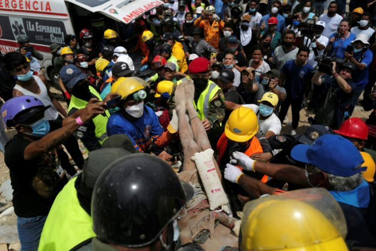 Des secouristes transportent une personne extraite vivante des décombres d'un immeuble effondré à Caraballeda, dans l'État de La Guaira, le 28 juin 2026 après deux séismes meurtrier, au Venezuela ( AFP / Mauricio VALENZUELA )