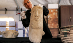 Une membre de l'association Mayasem pour la culture et les arts nettoie un artefact à la brosse, sous une tente à Khan Younès, dans le sud de la bande de Gaza, le 11 juillet 2026 ( AFP / Bashar Taleb )