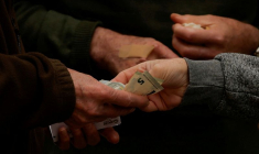 Un client paie un vendeur de loterie de rue avec des billets de cinq euros