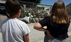 Des élèves regardent des fleurs déposées sur les grilles du collège Françoise-Dolto à Nogent, en Haute-Marne, au lendemain du meurtre d'une surveillante, le 11 juin 2025 ( AFP / FRANCOIS NASCIMBENI )
