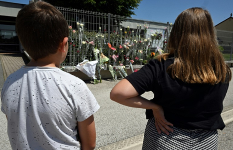 Des élèves regardent des fleurs déposées sur les grilles du collège Françoise-Dolto à Nogent, en Haute-Marne, au lendemain du meurtre d'une surveillante, le 11 juin 2025 ( AFP / FRANCOIS NASCIMBENI )