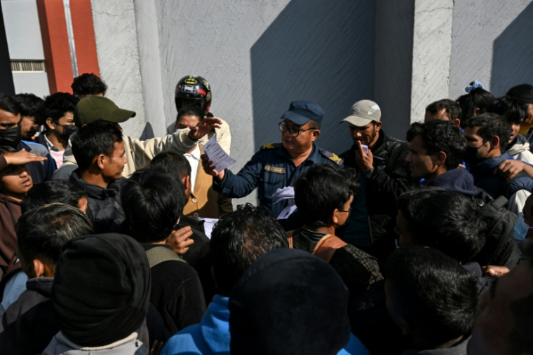 Des jeunes rassemblés autour d'un officier de police pour déposer des demandes d'emploi de policiers temporaires avant les prochaines élections générales, devant le commissariat de police du district de Katmandou, le 11 janvier 2026 au Népal ( AFP / Prakash MATHEMA )