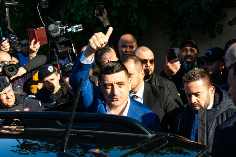 Le chef du parti nationaliste AUR et candidat à la présidence roumaine, George Simion, salue ses partisans après avoir voté à Mogosoaia, près de Bucarest, le 18 mai 2025 ( AFP / Mihai Barbu )
