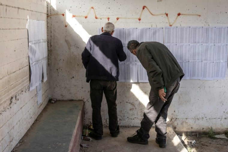 Deux hommes consultent les listes électorales dans un bureau de vote lors des élections municipales du village de Qabatiyah, au sud de Jénine, en Cisjordanie occupée par Israël, le 25 avril 2026 ( AFP / JOHN WESSELS )