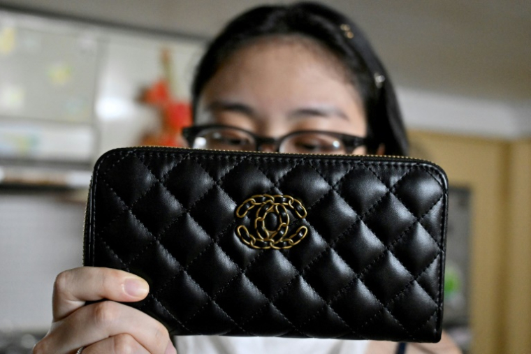 Une femme tient un sac Chanel contrefait, chez elle à Hanoï, le 10 juin 2025 au Vietnam ( AFP / Nhac NGUYEN )