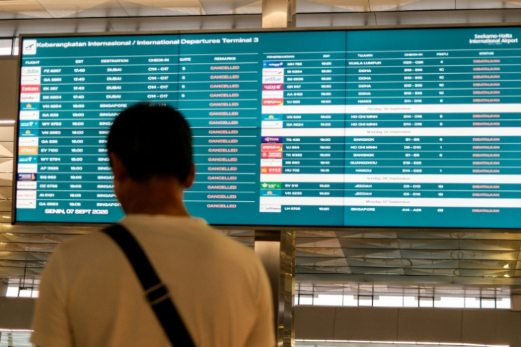 Un passager bloqué à l'aéroport international Soekarno-Hatta en raison de l'éruption du volcan Anak Krakatau, regarde un écran d'information sur les vols, le 7 septembre 2026 à Tangerang, en Indonésie ( AFP / Taris HIRZIMAN )