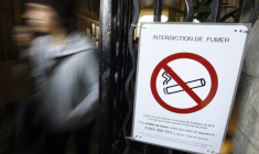 Des écoliers passent devant un panneau d'interdiction de fumer dans leur école à Nice