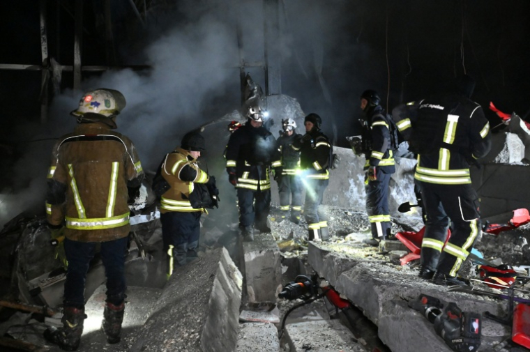 Des pompiers sur le site d'un entrepôt de la compagnie postale Nova Poshta endommagé par un bombardement russe dans un village près de Kharkiv, le 13 janvier 2026 en Ukraine ( AFP / SERGEY BOBOK )