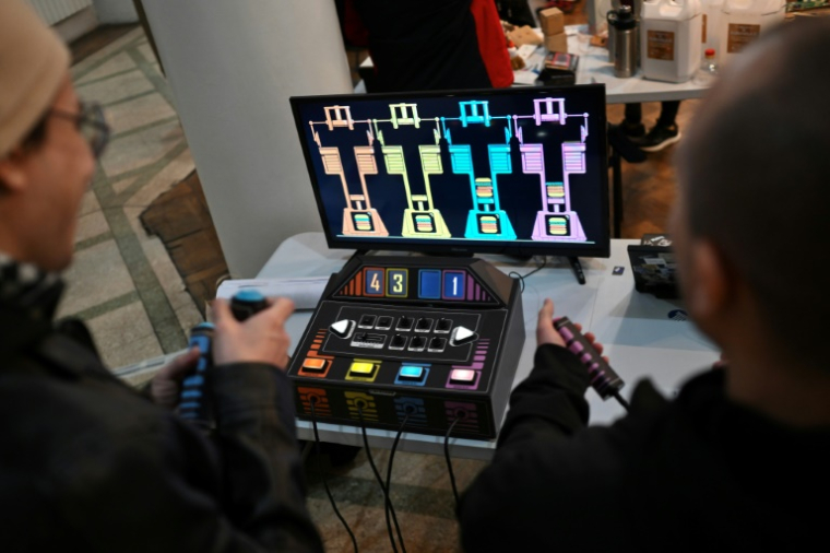 Des personnes jouent à un jeu vidéo fabriqué à partir de composants électroniques recyclés lors de la 3e Rencontre fédérale Cyberciruja à Buenos Aires, le 16 août 2025 en Argentine ( AFP / Luis ROBAYO )