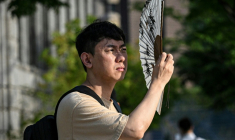 Un homme se protège du soleil avec un éventail, le 13 juillet 2026 à Séoul  ( AFP / JADE GAO )