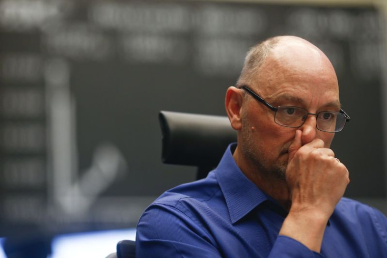 Un trader réagit à son bureau devant le tableau du DAX à la bourse de Francfort