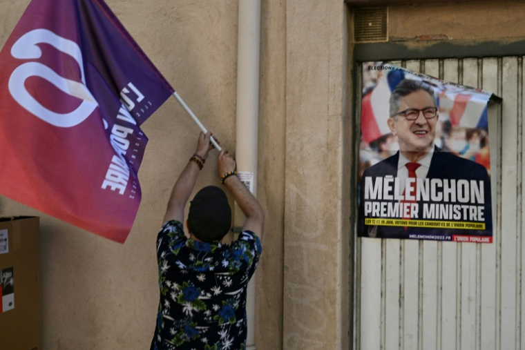 Un drapeau de la France insoumise (LFI) et une affiche électorale montrant Jean-Luc Mélenchon à Marseille, le 12 mai 2022 ( AFP / Pascal GUYOT )