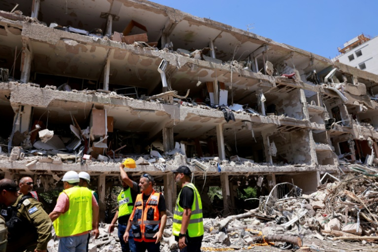 Des secouristes israéliens devant un bâtiment détruit après une frappe iranienne, le 22 juin 2025 à Tel-Aviv ( AFP / Menahem Kahana )