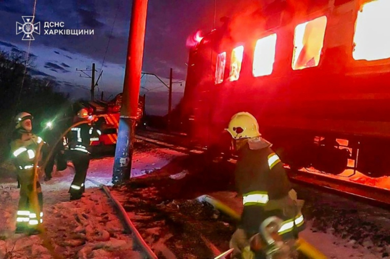 Photo prise et fournie par les secours ukrainiens le 27 janvier 2026, montrant des pompiers essayant d'éteindre les flammes dans un train ukrainien après une frappe russe dans la région de Karkhiv (nord-est de l'Ukraine) ( UKRAINIAN EMERGENCY SERVICE / Handout )