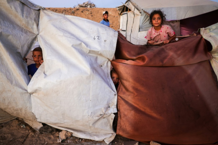 Des enfants palestiniens posent pour une photo près de leur abri de fortune à Khan Younès, dans le sud de la bande de Gaza, le 25 octobre 2025 ( AFP / Bashar TALEB )