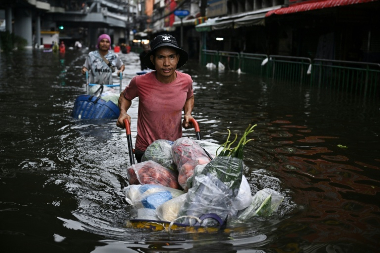 Des vendeurs transportent des marchandises à travers les eaux en crue dans le district de Bang Kapi à Bangkok, le 28 septembre 2026 ( AFP / Lillian SUWANRUMPHA )